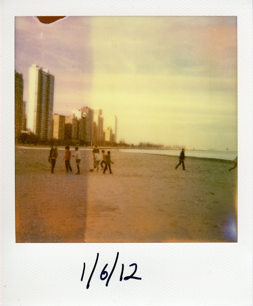 A Polaroid photo of Chicago's coast as seen looking north from Oak Street Beach. The leftmost hird of the image is exposed darker and more colorful.